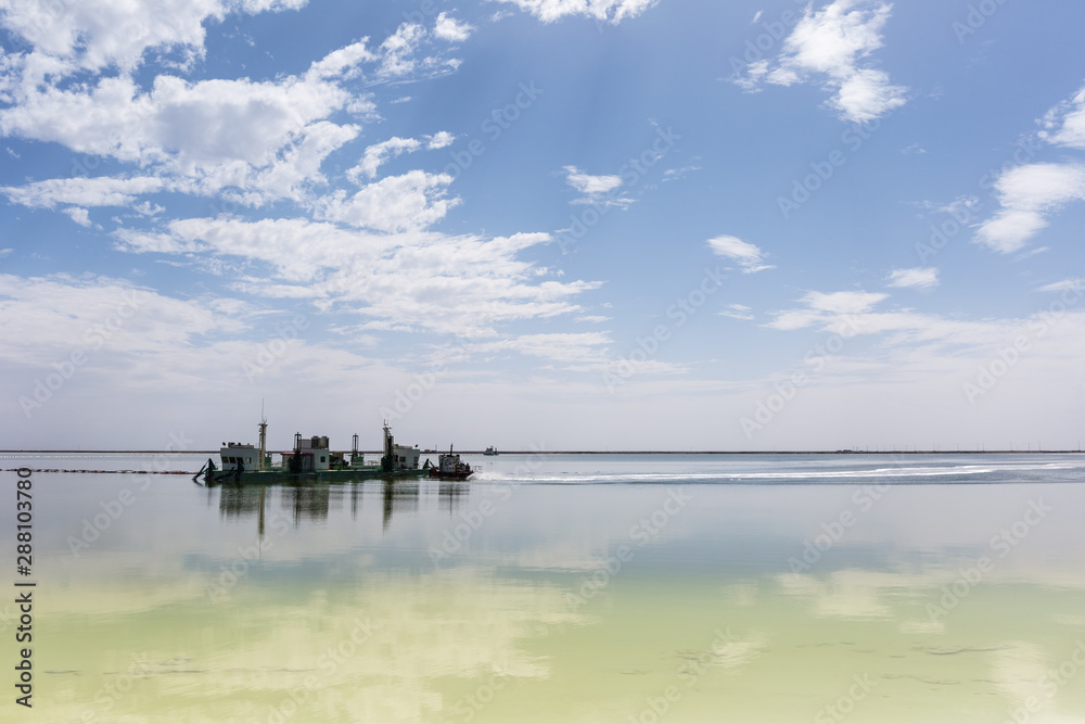 salt mining ship and blue sky reflection in qarhan salt lake