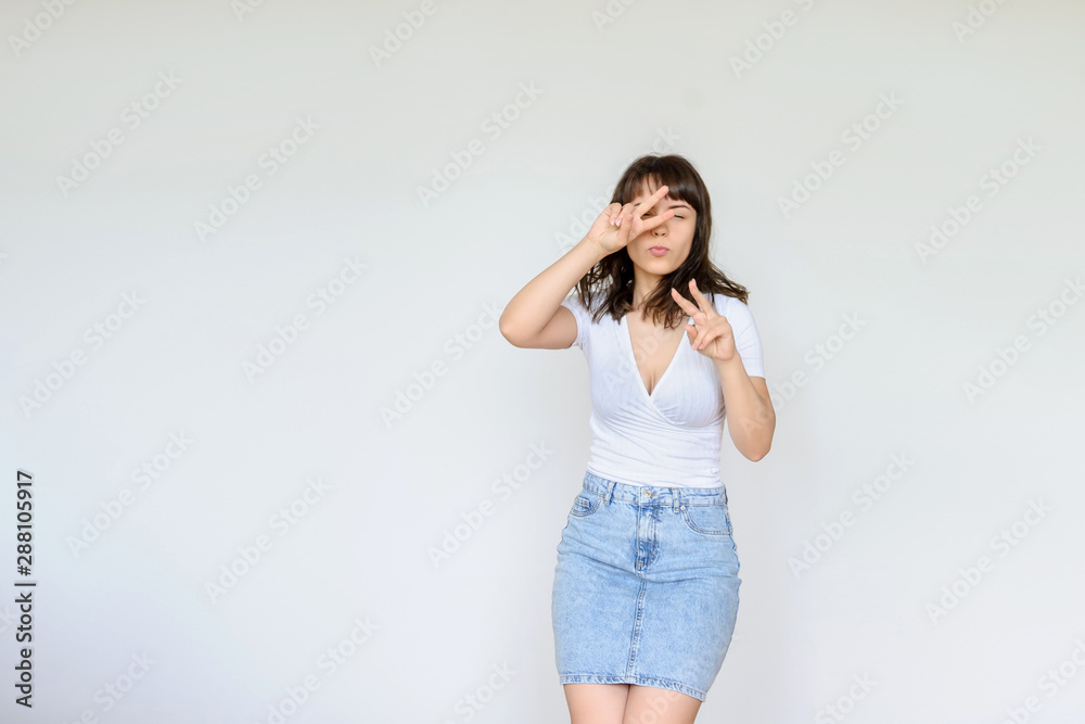close up photo of a happy brunette in white blouse and denim skirt jumping in the air