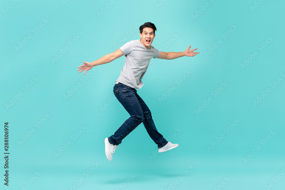 Energetic happy young Asian man in casual clothes jumping