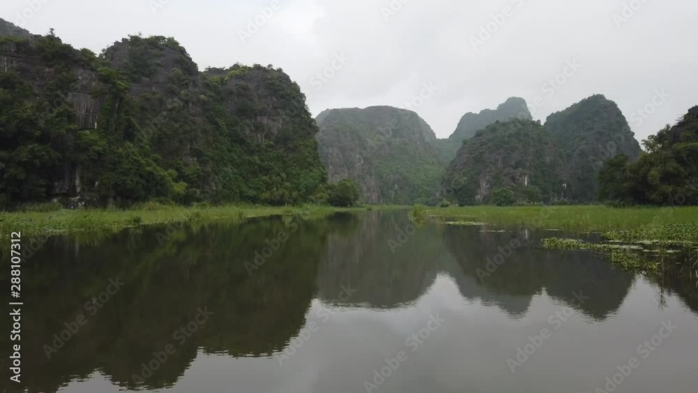 Exploring Tam Coc by rowing boat early morning. Beautiful landscape surounded by karst mountains and a famous UNESCO World Heritage site in north Vietnam Exploring Tam Coc by rowing boat early morning. Beautiful landscape surounded by karst mountains and a famous UNESCO World Heritage site in north Vietnam
