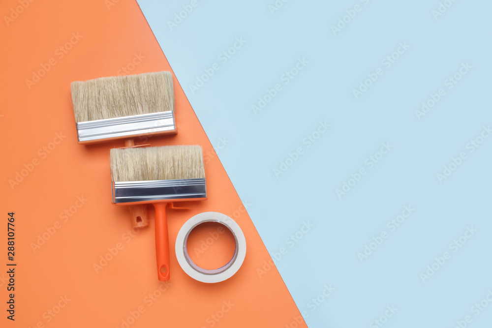 Two wide paint brushes, and masking tape. Work tools of the painter to create a trendy interior. Repair and room design minimal concept. Flat lay, top view, copy space. Two wide paint brushes, and masking tape. Work tools of the painter to create a trendy interior. Repair and room design minimal concept. Flat lay, top view, copy space.