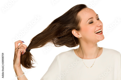 young happy woman takes off the rubber band from her hair on white background photo