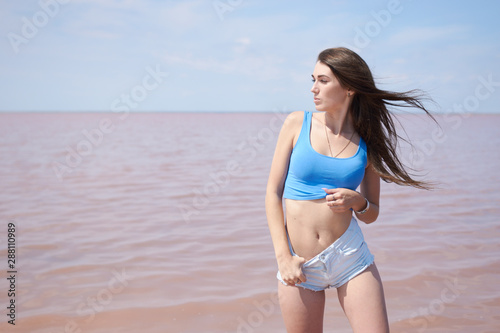 Fototapeta Naklejka Na Ścianę i Meble -  Sexy young woman posing near the pink lake