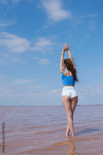 Sexy young woman posing near the pink lake