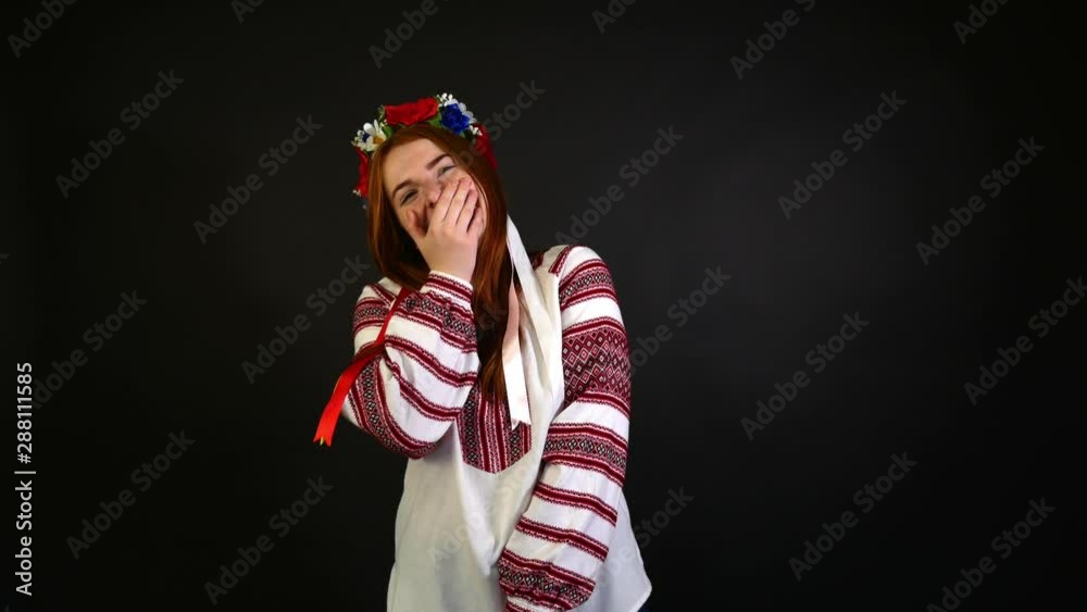 Happy red-haired girl in an embroidered shirt laughs out loud. Black background Happy red-haired girl in an embroidered shirt laughs out loud. Black background