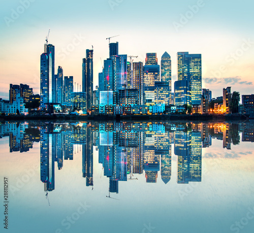 Canary Wharf business and banking area at sunset with beautiful reflection in the River Thames water. London, UK