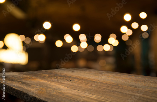 Empty wood table top on blur light gold bokeh of cafe restaurant in dark background