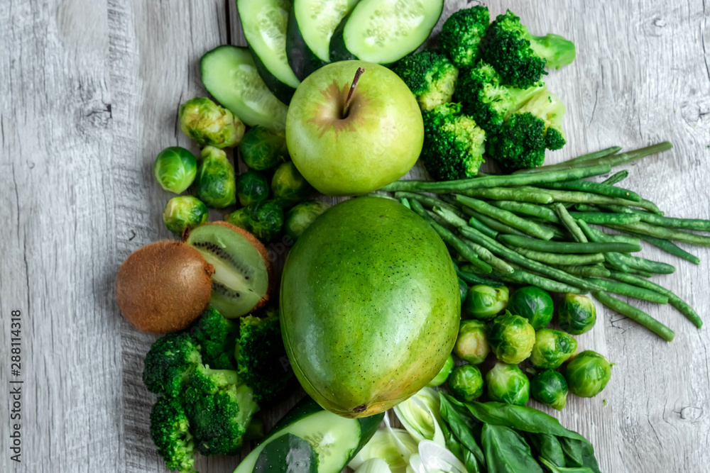 Fresh green food on a light table. Avocados cucumbers cabbage apples beans kiwi onions broccoli. The concept of healthy food, detox vegetarianism. Copy space flat lay. Fresh green food on a light table. Avocados cucumbers cabbage apples beans kiwi onions broccoli. The concept of healthy food, detox vegetarianism. Copy space flat lay.
