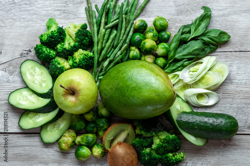 Fresh green food on a light table. Avocados cucumbers cabbage apples beans kiwi onions broccoli. The concept of healthy food, detox vegetarianism. Copy space flat lay.