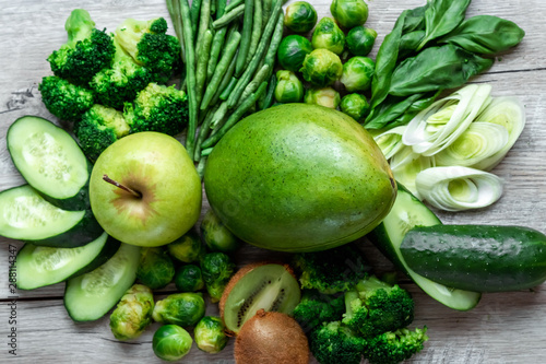 Fresh green food on a light table. Avocados cucumbers cabbage apples beans kiwi onions broccoli. The concept of healthy food, detox vegetarianism. Copy space flat lay.