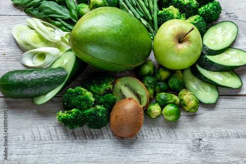 Fresh green food on a light table. Avocados cucumbers cabbage apples beans kiwi onions broccoli. The concept of healthy food  detox vegetarianism. Copy space flat lay.