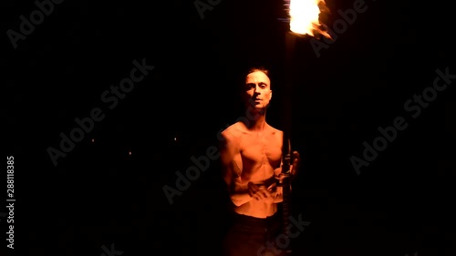 Fire show. Man juggles with two burning torches. Night show. Mastery of the fakir. Close-up photo