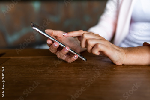 Using mobile phone. Woman using smart phone in cafe. Surfing the net. Business women hand are using cell phones in office. Close up of hands using mobile application on smartphone