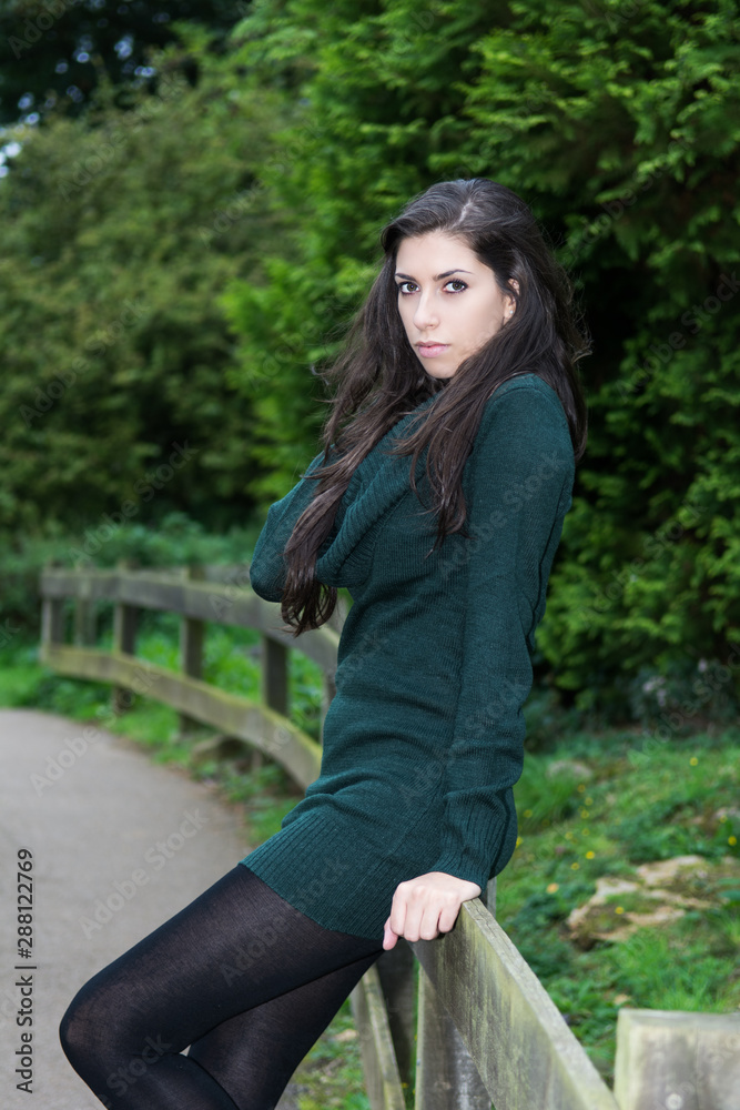 Autumnal scene. Brunette adult model. Fashion style woman with long brunette hair wearing green knitted dress wool clothes.