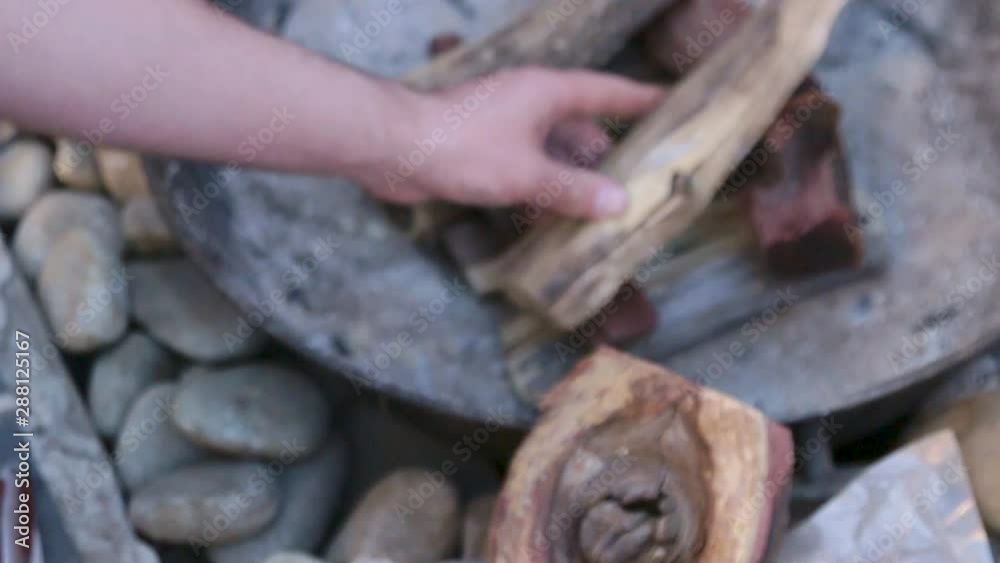 Man places wood on a fire for a barbeque Man places wood on a fire for a barbeque