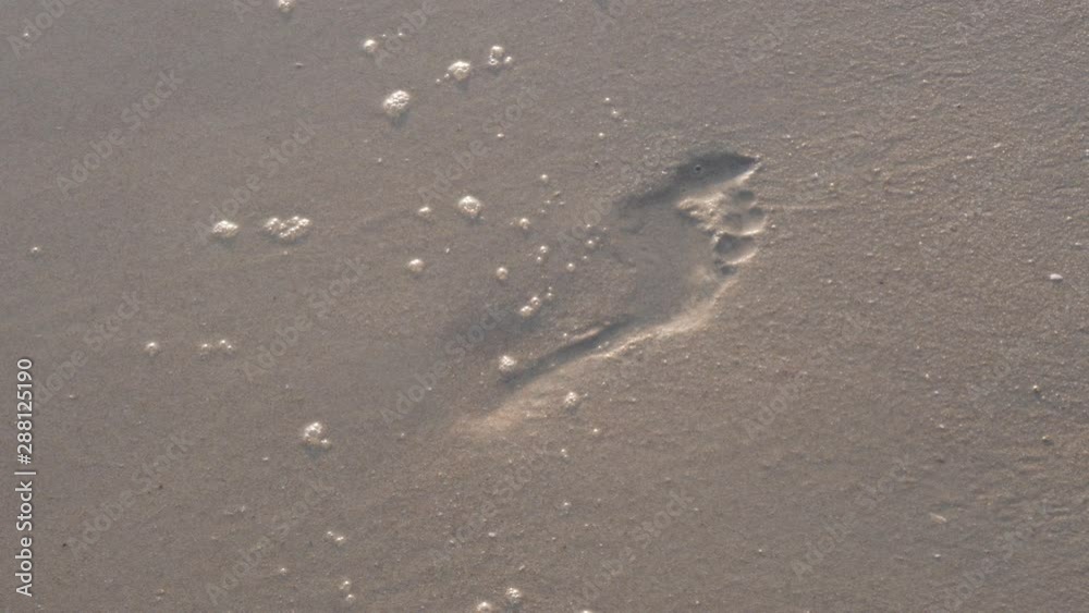 Footprint on the sand with wave reaching it Footprint on the sand with wave reaching it
