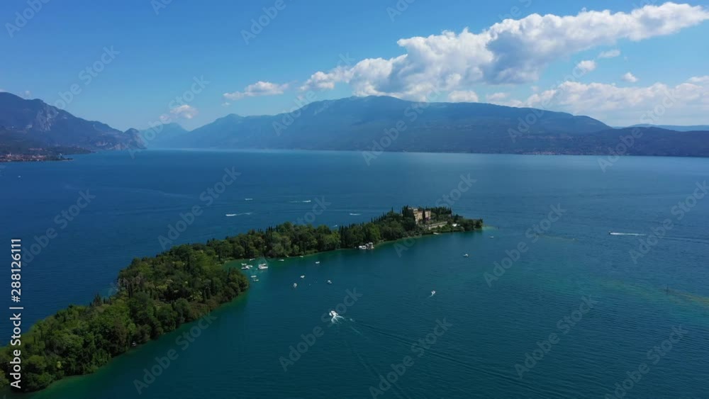 Unique view of the island of Garda. In the background is the Alps. Resort place on Lake Garda north of Italy. Aerial video with drone. Isola del Garda. Unique view of the island of Garda. In the background is the Alps. Resort place on Lake Garda north of Italy. Aerial video with drone. Isola del Garda.
