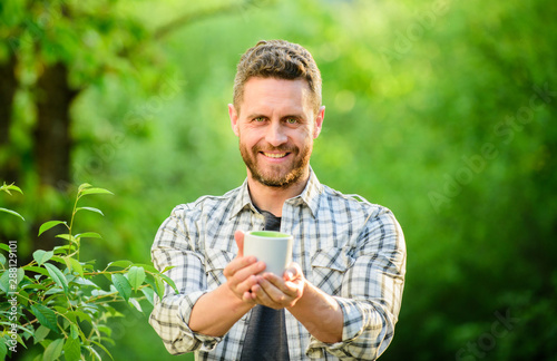 I prefer green tea. Refreshing drink. Man bearded tea farmer hold mug nature background. Green tea plantation. Whole leaf tea. Pleasant moment of self care. Natural drink. Healthy lifestyle