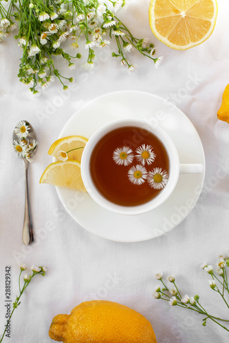 Treating a cold or flu. Traditional medicine, hot tea with herbs and lemon. Chamomile tea. A light still life in the style of Provence. Flat lay, selective focus.