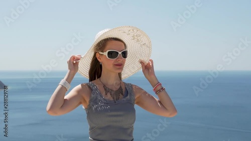 Close - up of European vacation woman in a white hat with a wide brim. A woman admires a delightful view of the sea from the high mountains in Europe. photo