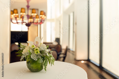 Fancy bouquet with exotic flowers in green round vase on table in reception hall