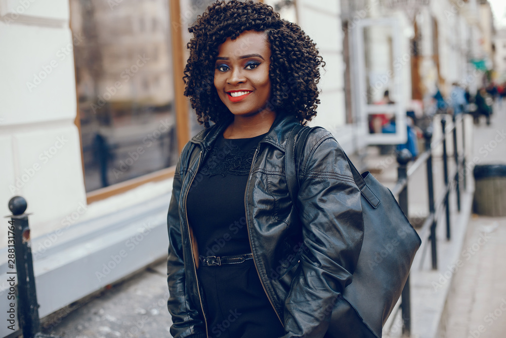 Fototapeta premium elegant and stylish dark-skinned girl with curly hair walking around the summer city