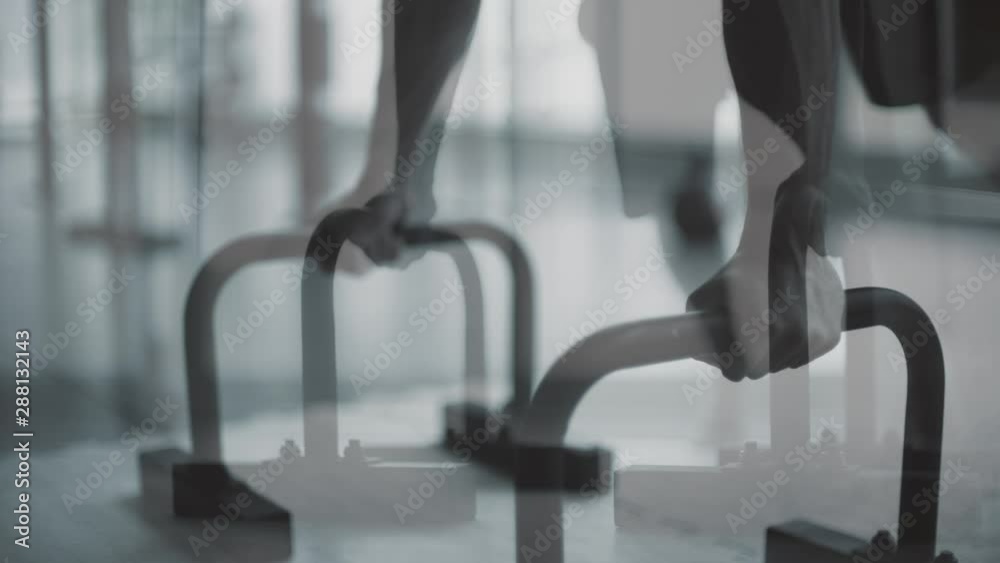 Muscular man working out on dip bars at the gym