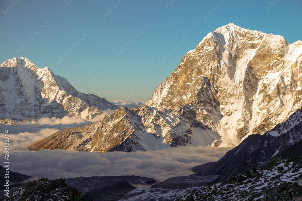 View of Lobuche mountain in the early morning from the summit of Kala Patthar in Nepal. The valley at the base of the mountain is covered with clouds. Nature, mountains, sunset and sunrise concept.