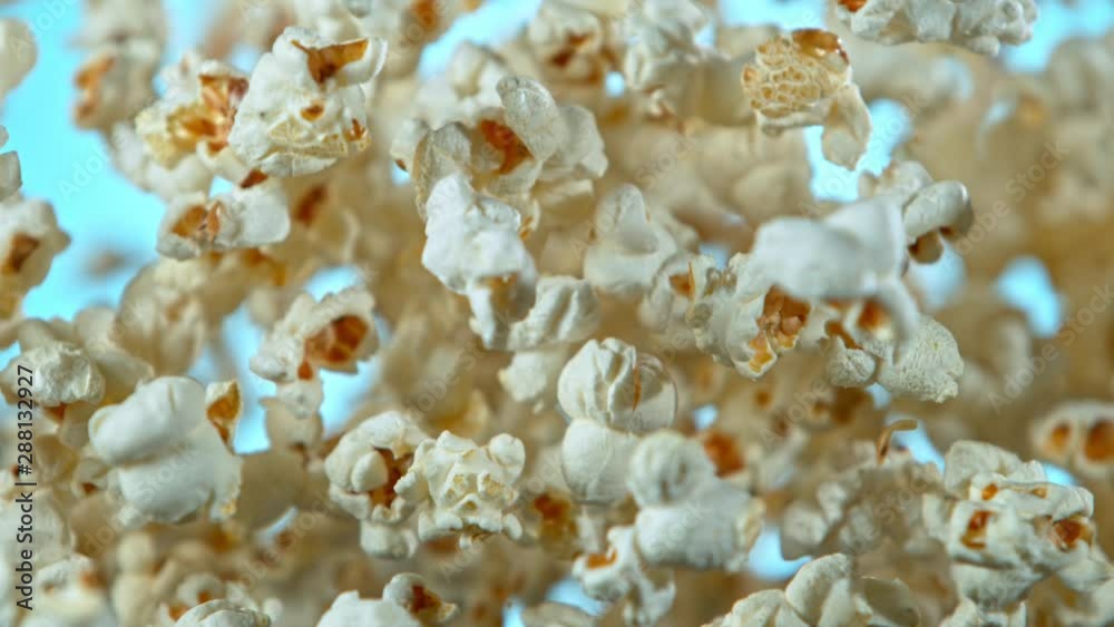 Super Slow Motion Shot of Popcorn on Blue Background after being Exploded at 1000fps. Shooted with High Speed Cinema Camera at 4K. Super Slow Motion Shot of Popcorn on Blue Background after being Exploded at 1000fps. Shooted with High Speed Cinema Camera at 4K.