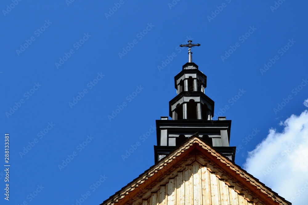 Church roof with a cross. Church building roof with a holy cross. Top of local country church roof with holy cross against blue sky