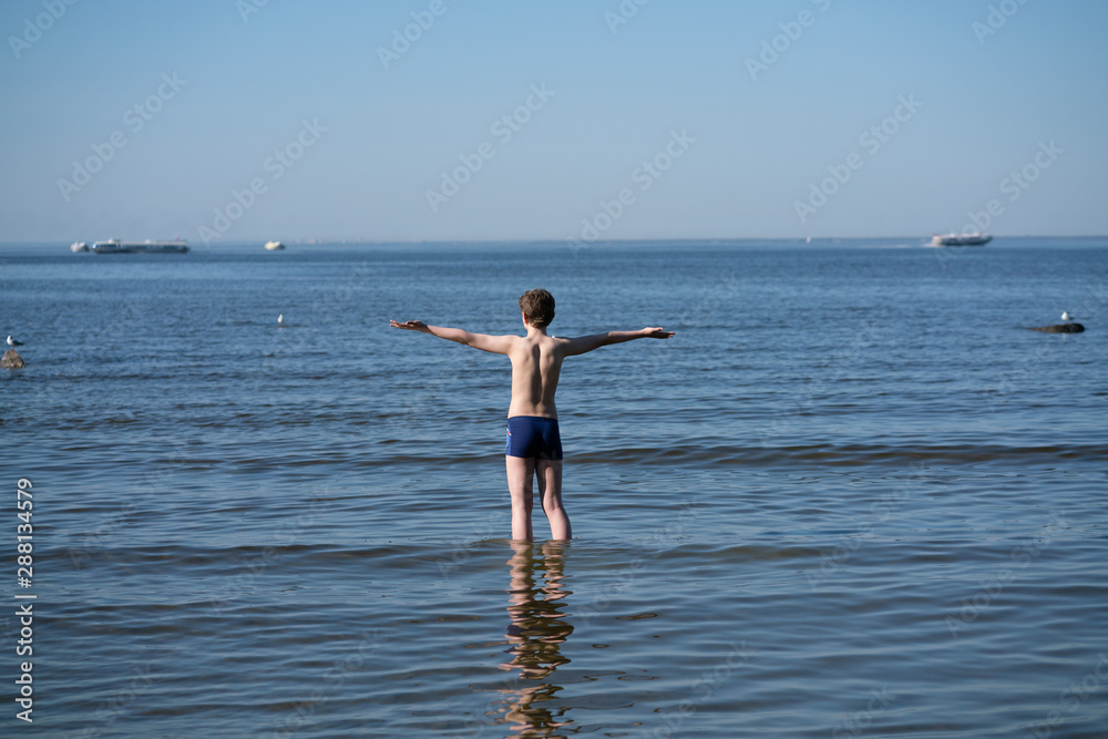 Silhouette of child on the beach, holding his hands up