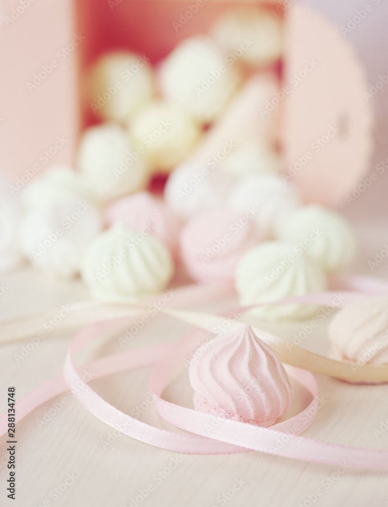 Pastel romantic background with scattered little meringues in a box, flower and ribbons Pastel romantic background with scattered little meringues in a box, flower and ribbons