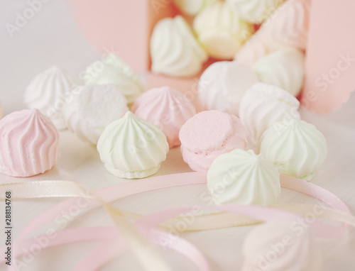 Pastel romantic background with scattered little meringues in a box, flower and ribbons