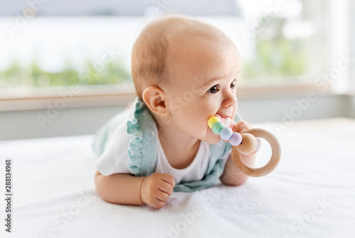 Obraz na plátne teething, babyhood and people concept - sweet little baby girl lying on white bl