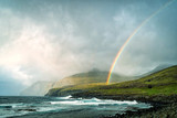 Dramatic landscape of Faroe Island with stormy clouds and rainbow.