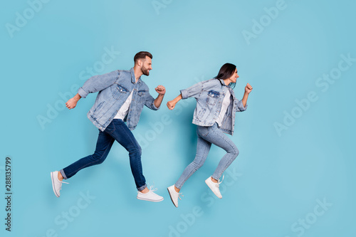 Full length body size photo of funny enjoying nice good cute couple wearing jeans denim clothes having contests at fast running while isolated with blue background