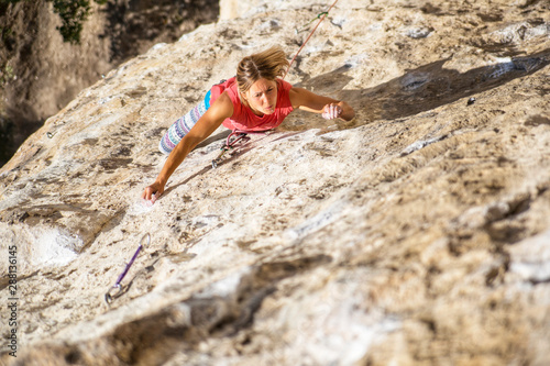 Climber overcomes challenging climbing route. A girl climbs a rock. Woman engaged in extreme sport. Extreme hobby.