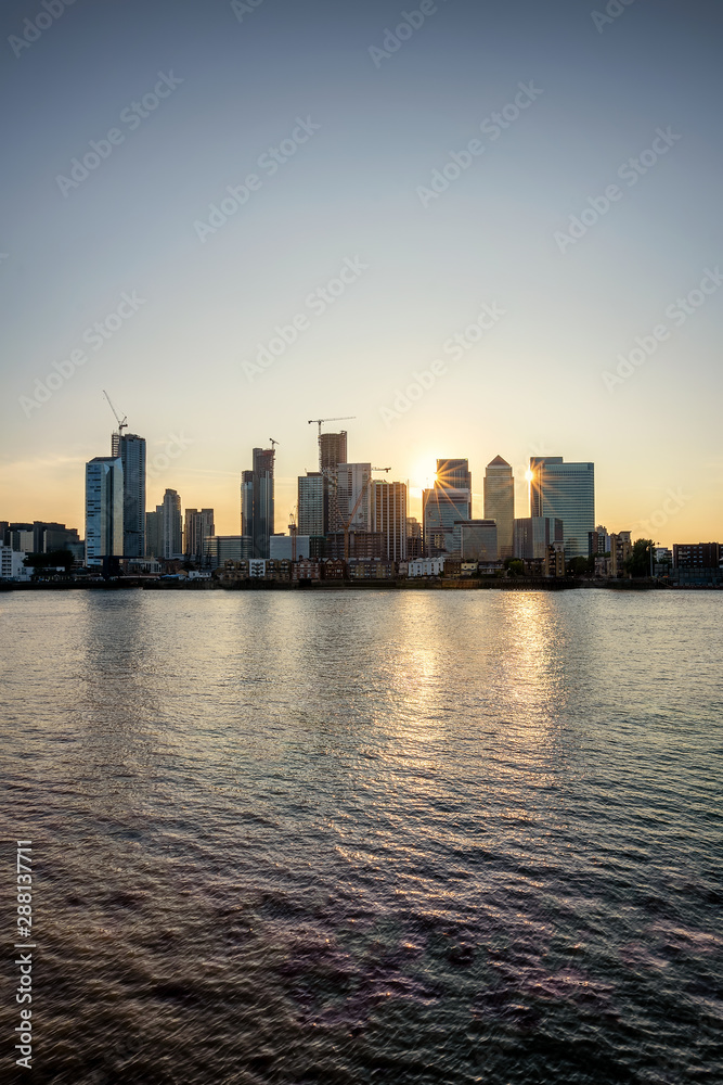 Blick über die Themse auf die Hochhäuser des Bezirkes Canary Wharf in London zum Sonnenuntergang