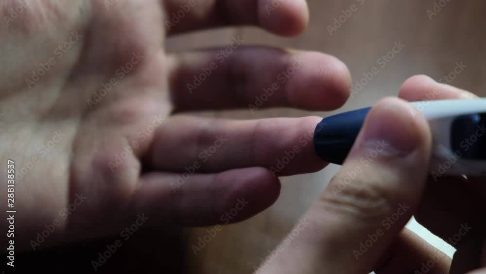 Diabetic man piercing finger to measure blood glucose. Measuring blood sugar with a glucometer Diabetic man piercing finger to measure blood glucose. Measuring blood sugar with a glucometer