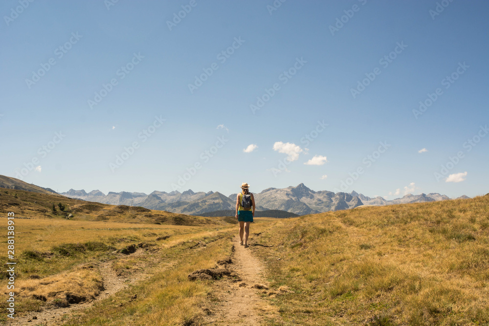 Woman hiking through a high mountain valley