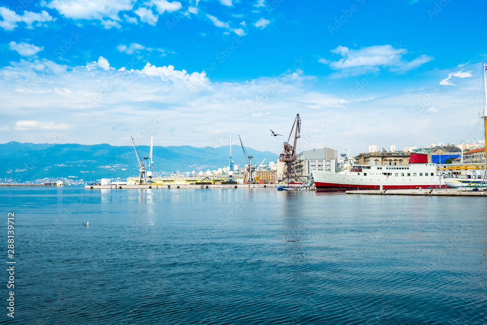 Croatia, city of Rijeka, ciew of harbor, seascape and skyline of the city center and old port cranes, blue sky with clouds