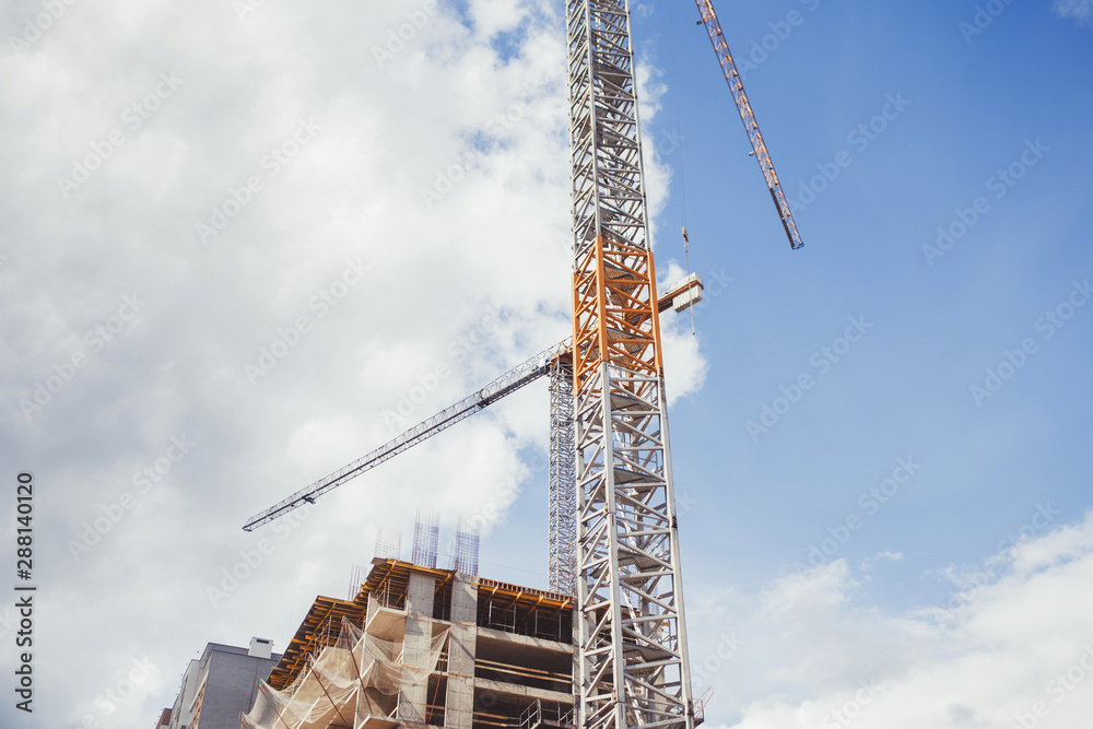 Cranes and building under construction against sky Cranes and building under construction against sky