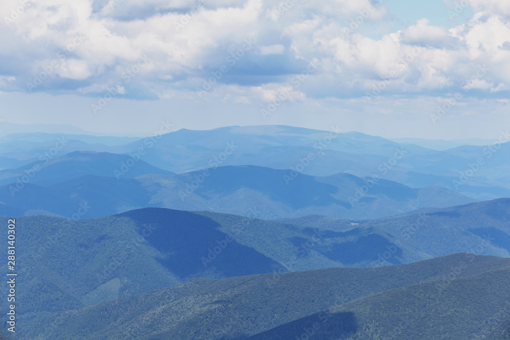 Landscape of Carpathian Mountains with blue silhouettes of hills and mountains with blue sky.
