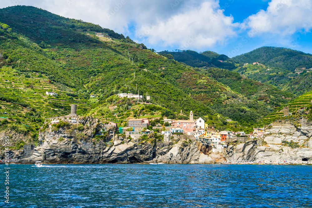 The rocky shore of Cinque Terre, overgrown with tropical greenery and vineyards. View from the sea, authentic city buildings, Monterosso al Mare, Italy