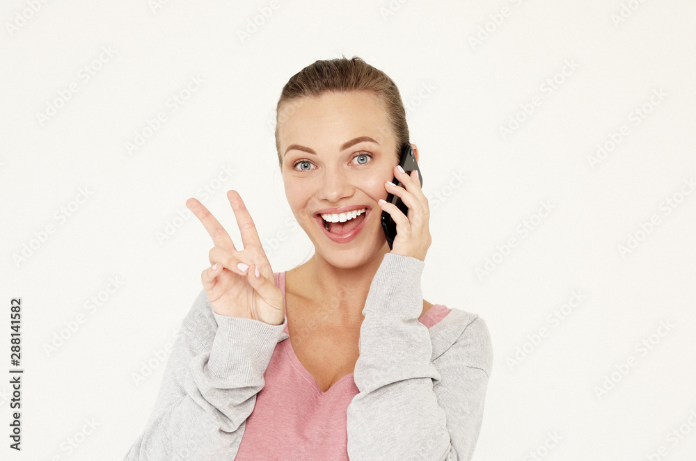 A beautiful young blonde woman picks up the news on the phone and is surprised. Great news! Over white background. A beautiful young blonde woman picks up the news on the phone and is surprised. Great news! Over white background.