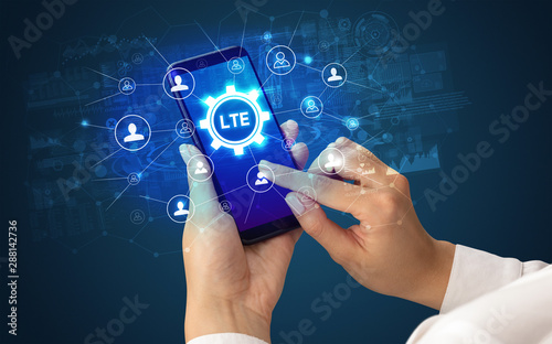 Female hand holding smartphone with LTE abbreviation, modern technology concept photo