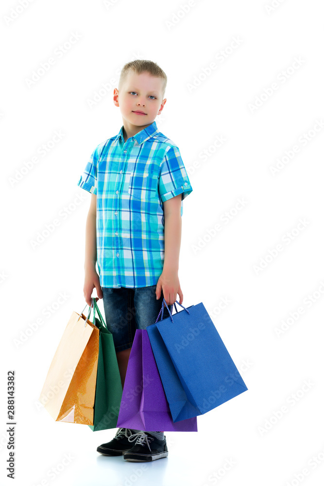 Little boy waving multicolored paper bags. He goes shopping Little boy waving multicolored paper bags. He goes shopping