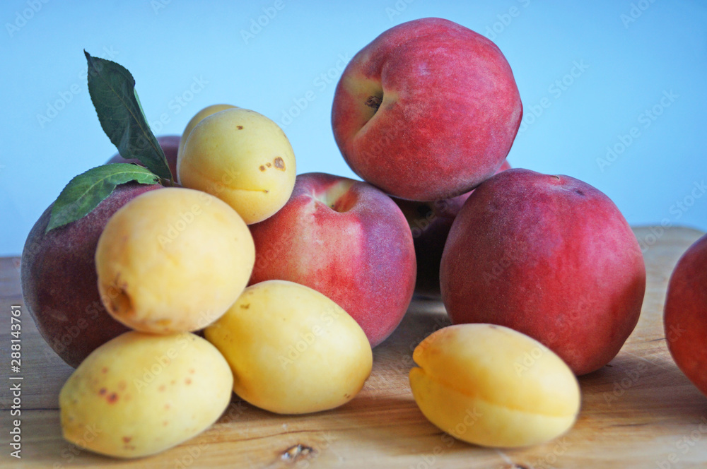 Ripe and juicy apricots and peaches with yellow and orange peels lie on a wooden table Ripe and juicy apricots and peaches with yellow and orange peels lie on a wooden table