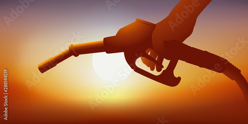 Concept de la production de pétrole et  de la guerre économique mondiale avec une main tenant le pistolet d’une pompe à essence.