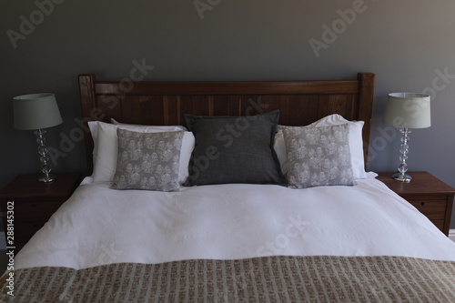 Table lamp and pillows arranged on a bed in bedroom